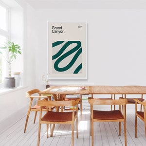 May include: A framed art print with the words "Grand Canyon" in a minimalist style. The artwork features a teal abstract design on a cream background. The print is displayed in a bright, modern dining room setting with wooden furniture.