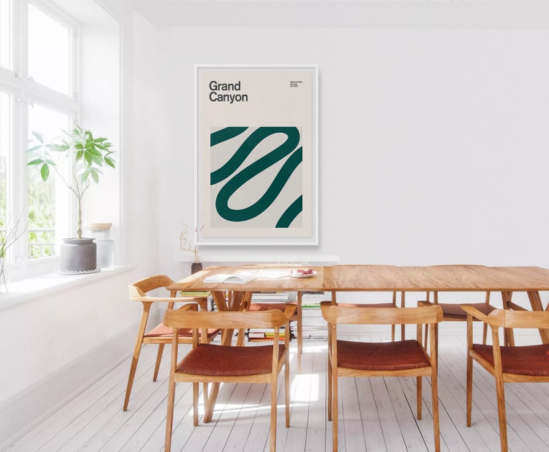 May include: A framed art print with the words "Grand Canyon" in a minimalist style. The artwork features a teal abstract design on a cream background. The print is displayed in a bright, modern dining room setting with wooden furniture.