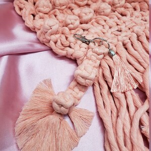 May include: A pink crocheted keychain with a tassel and a key ring. The keychain is made of soft, fluffy yarn and has a delicate, feminine look.