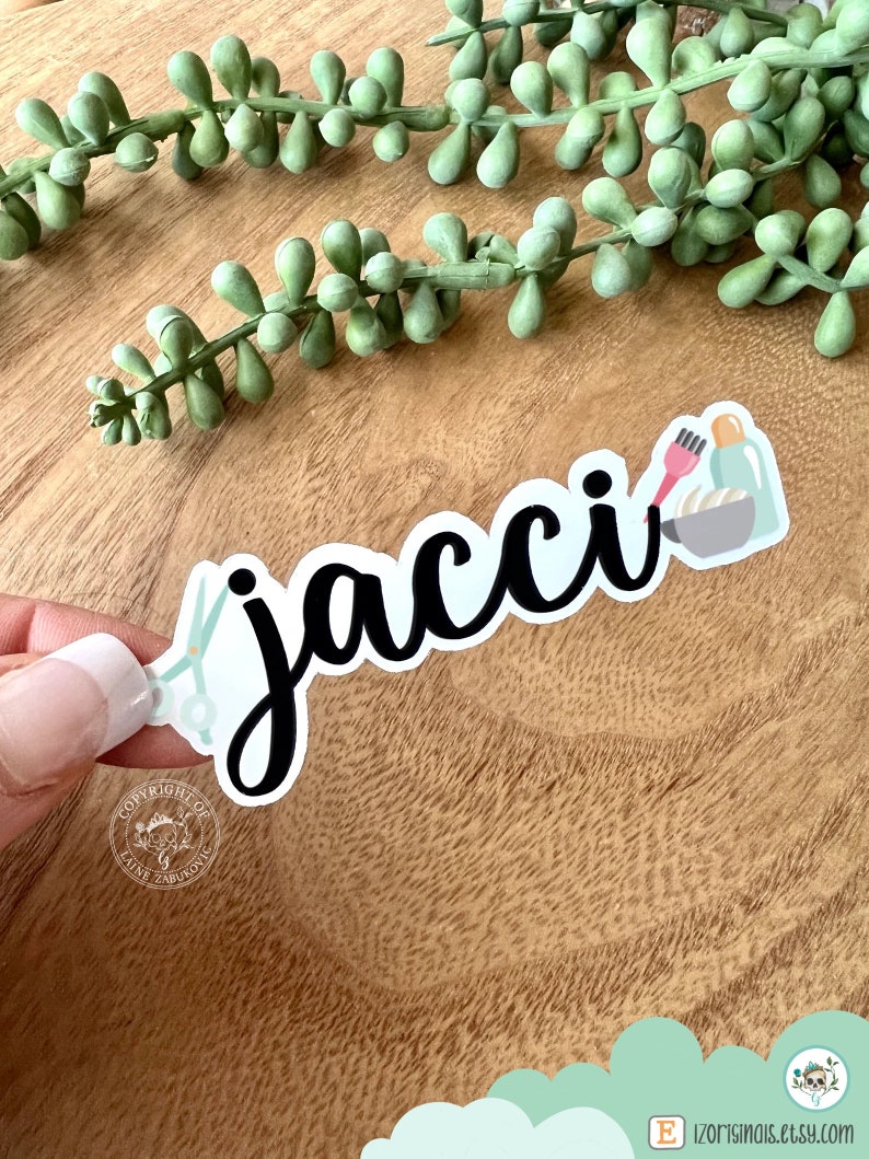 K&ouml;nnte beinhalten: Ein wei&szlig;er Aufkleber mit dem Namen "jacci" in schwarzer Kursivschrift. Der Aufkleber zeigt eine Schere, eine Haarb&uuml;rste und eine Flasche Haarf&auml;rbemittel, was auf ein Thema f&uuml;r Friseure oder Salons hindeutet.