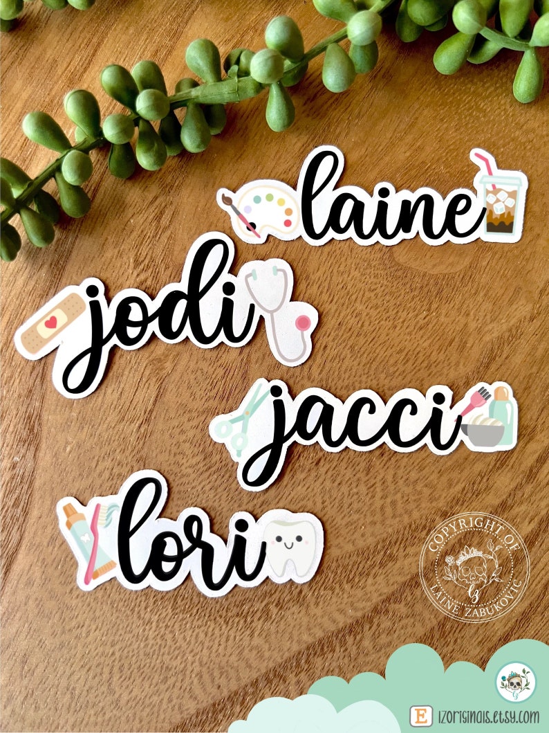 K&ouml;nnte beinhalten: F&uuml;nf personalisierte Namenaufkleber mit verschiedenen Symbolen. Die Namen sind "JODI", "LAINE", "JACCI", "LORI" und ein Copyright-Symbol mit dem Text "COPYRIGHT OF LAINE ZABUKOVIC".