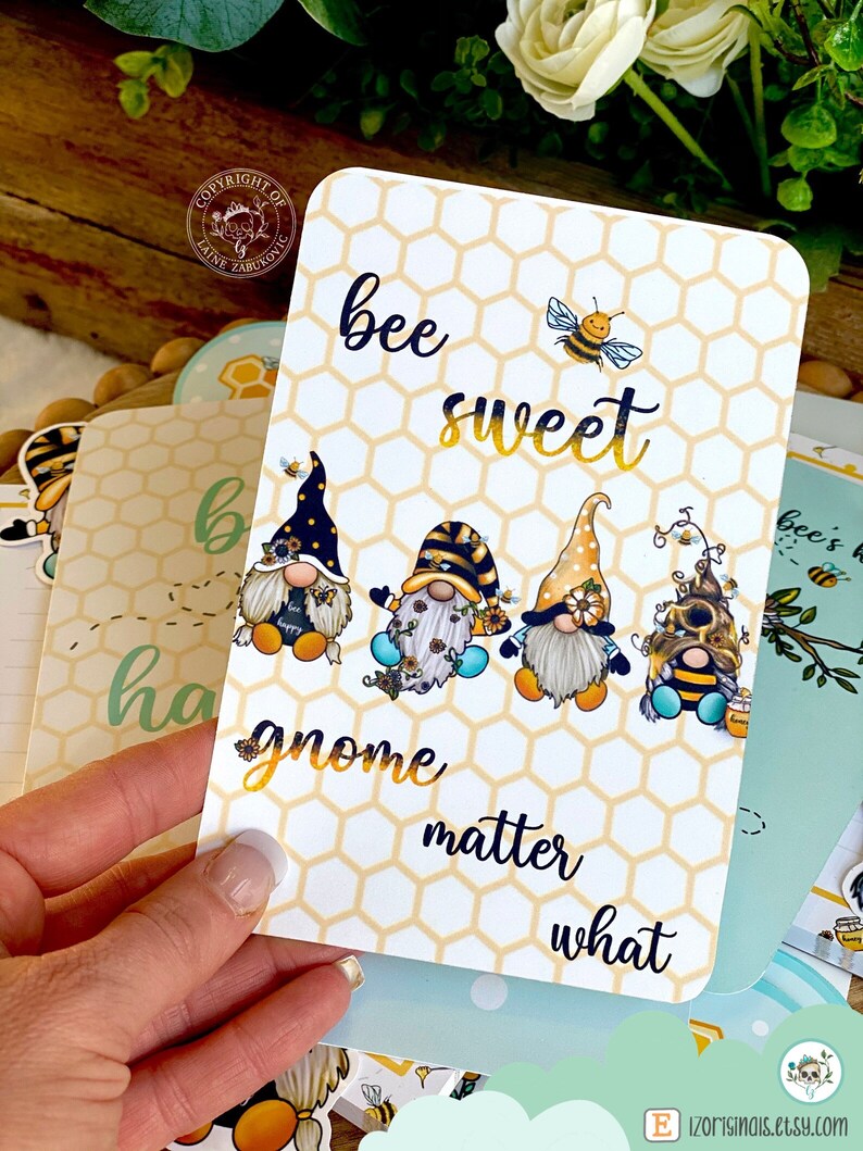 May include: A white card with a honeycomb pattern and the text "bee sweet gnome matter what". There are four gnomes with bee wings and a bee on the card.