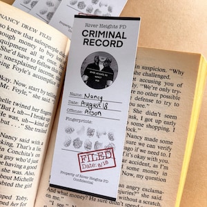 May include: A white card with a black and white photo of a woman with a black and white background. The card has the text "River Heights PD Criminal Record" in black text. The card also has the text "Name: Nancy, Date: August 18, Offense: Arson, Fingerprints: " in black text. The card has a red stamp that says "Filed Date: 8/18" in white text.