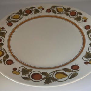May include: Off-white oval serving platter with a brown and orange border. The rim features a repeating pattern of stylized pears, apples, and leaves in shades of yellow, orange, and brown. A classic design for serving food.