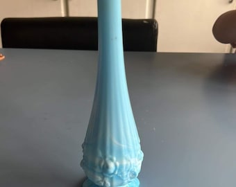 May include: A light blue glass vase with a ruffled, scalloped base and a textured, ribbed body. The vase is decorated with raised white flowers.
