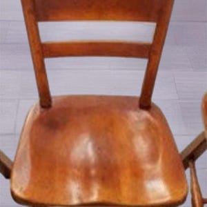 May include: A wooden chair with a brown finish. The chair has a high back with a cutout in the top and a slatted back.