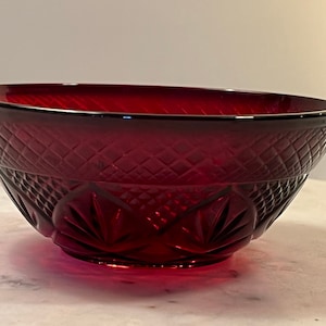 Puede incluir: Un tazón de vidrio rojo oscuro con un patrón de diamante y un borde festoneado.