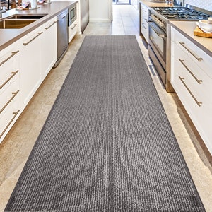 May include: A gray and white striped runner rug in a kitchen with white cabinets and stainless steel appliances.