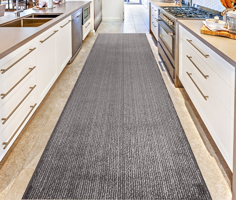 May include: A gray and white striped runner rug in a kitchen with white cabinets and stainless steel appliances.