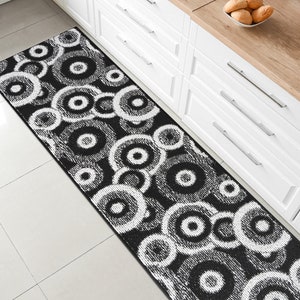 May include: Black and white patterned kitchen runner rug with a circular design. The rug is made of a soft, plush material and is perfect for adding a touch of style to any kitchen.