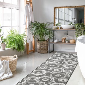 May include: A white bathroom with a white bathtub, a gray and white patterned bath rug, and a wooden shelf with a white sink and a mirror above it.