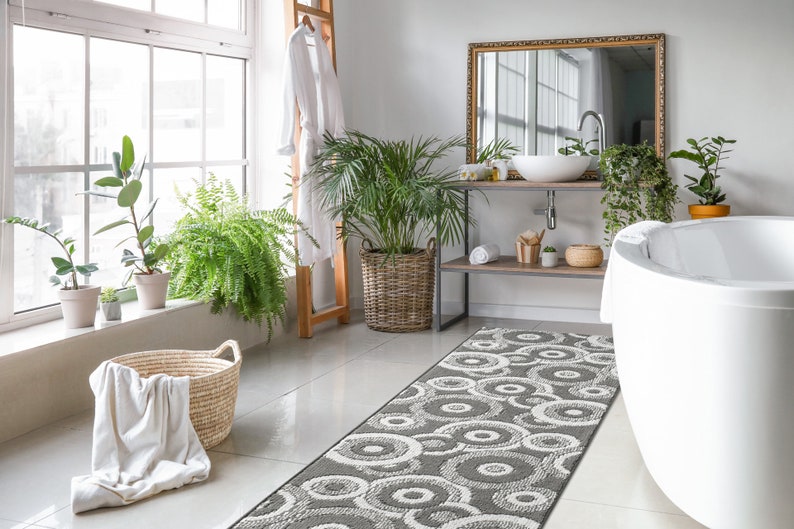 May include: A white bathroom with a white bathtub, a gray and white patterned bath rug, and a wooden shelf with a white sink and a mirror above it.
