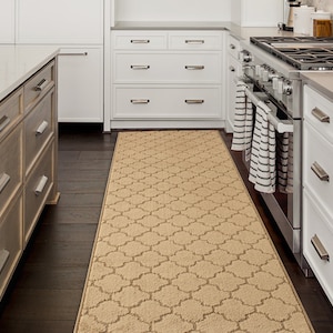 May include: A beige kitchen runner rug with a geometric pattern. The rug is placed in a kitchen with white cabinets and a stainless steel stove.