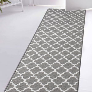 May include: A gray and white patterned runner rug with a geometric design. The rug has a subtle sheen and is made of a soft, plush material.