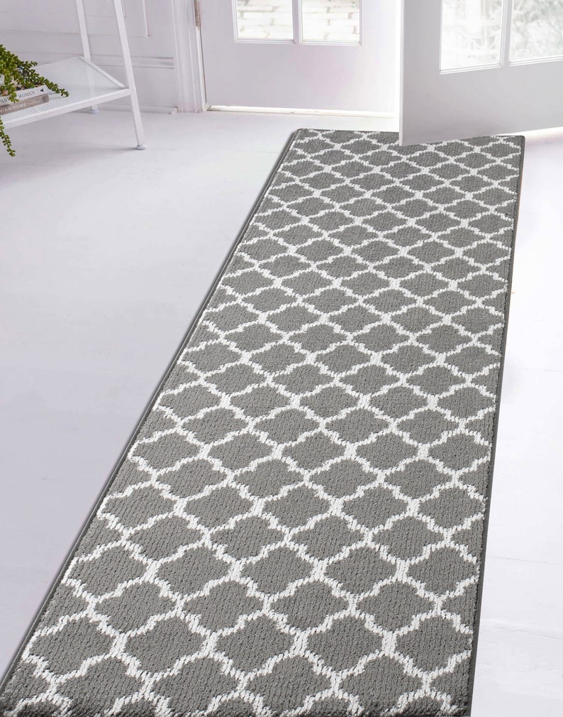 May include: A gray and white patterned runner rug with a geometric design. The rug has a subtle sheen and is made of a soft, plush material.