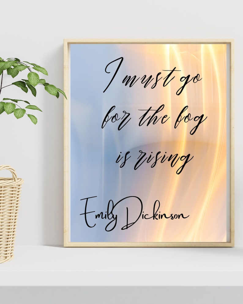May include: A framed print with a quote by Emily Dickinson: "I must go for the fog is rising". The background is a blurry image of a sunset with orange and yellow hues.