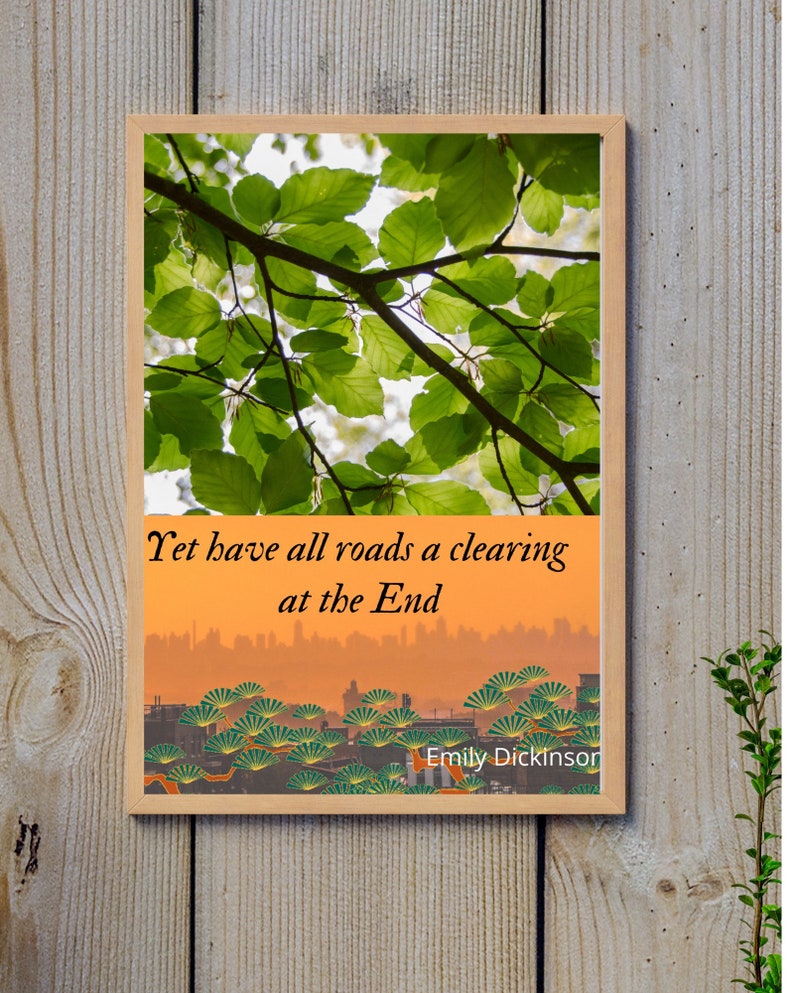 Op de afbeelding: Een ingelijst afdruk met een citaat van Emily Dickinson: "Yet have all roads a clearing at the End". De bovenste helft van de afdruk toont een foto van groene bladeren tegen een heldere lucht. De onderste helft van de afdruk toont een stadsbeeld met een zonsondergang op de achtergrond.