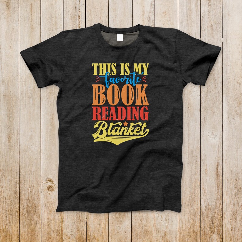 May include: A dark gray t-shirt with the text "This is my favorite book reading blanket" in a retro font with colorful accents.