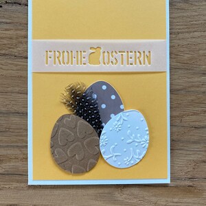 Osterkarte weiß gelb braun farbige Ostereier und Feder Gruß Frohe Ostern Karte
