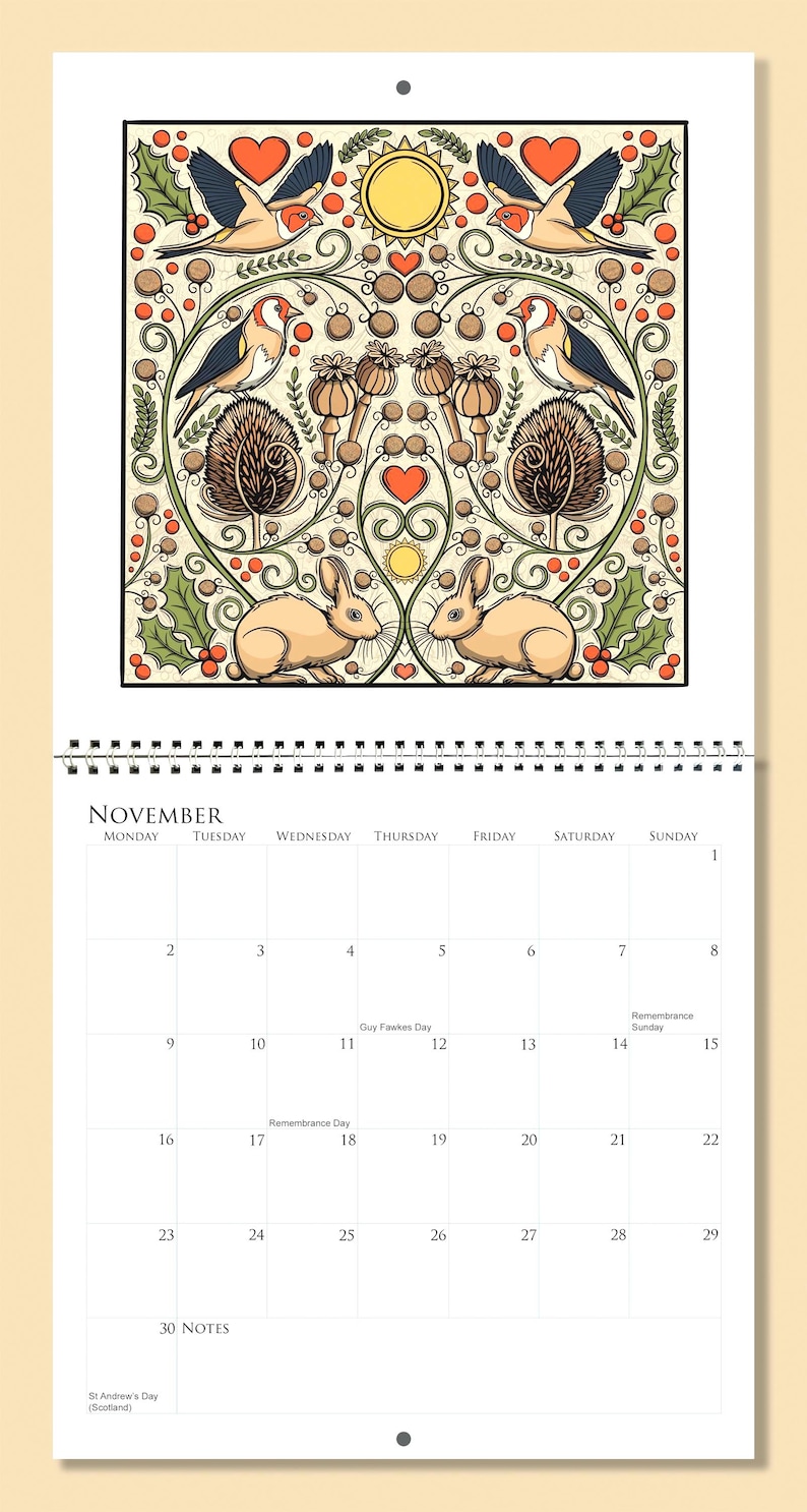 Op de afbeelding: Een kalenderpagina voor november met een decoratieve illustratie van vogels, konijnen en bloemmotieven. De kalender heeft een spiraalbinding en een cr&egrave;mekleurige achtergrond. De illustratie is symmetrisch.