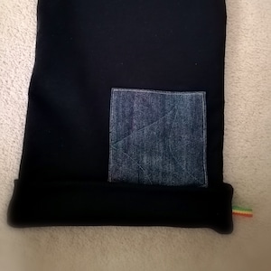 Peut inclure: Sac à cordon noir avec une poche en jean. Le sac a une bordure verte, jaune et rouge.
