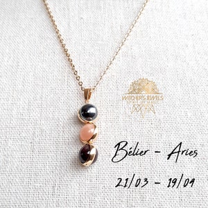 Peut inclure: Collier en chaîne dorée avec un pendentif composé de trois pierres empilées : hématite noire, pierre de lune rose et grenat rouge. Le pendentif est intitulé "Bélier - Aries 21/03 - 19/04".
