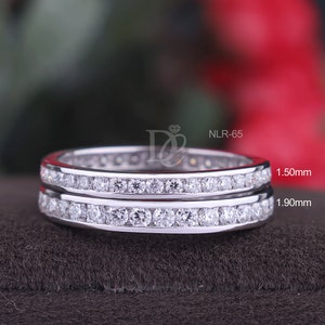 Peut inclure: Deux alliances en argent avec une rangée de petits diamants clairs. Les alliances sont superposées. L'alliance du haut mesure 1,50 mm de large et l'alliance du bas mesure 1,90 mm de large. NLR-65