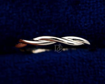 May include: A silver-colored, twisted ring. The ring has a braided design, with two strands intertwining to create a continuous loop. The ring is set against a dark blue background.
