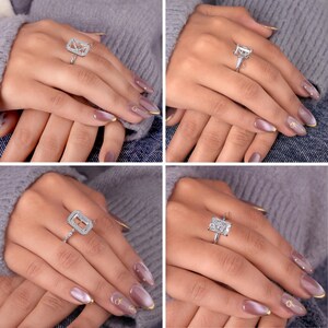 May include: A collection of four silver-toned rings featuring rectangular settings with clear, faceted stones. Each ring displays a distinct design, including halo settings and multi-stone arrangements, worn on fingers with mauve-coloured manicured nails.