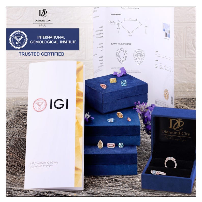 Op de afbeelding: Een verzameling losse gekleurde diamanten en twee ringen op gestapelde blauwe fluwelen doosjes. Een IGI-laboratoriumrapport voor in het lab gekweekte diamanten en een Diamond City-certificaat zijn zichtbaar, met details over proporties en zuiverheid.