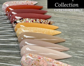 May include: A set of ten fall-themed nail dip powders in various shades of brown, orange, and pink. The powders are arranged in a row on a wooden surface. The text "Fall Bouquet Collection CN DESIGNER DIPS" is displayed at the top of the image.