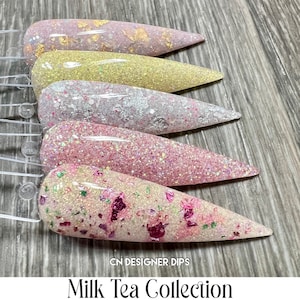 Puede incluir: Cinco colores de polvo de inmersión para uñas en una colección de té con leche. Los colores son un rosa claro con escamas doradas, un amarillo claro con purpurina, un blanco con purpurina plateada, un rosa claro con purpurina y un blanco con purpurina rosa y verde.