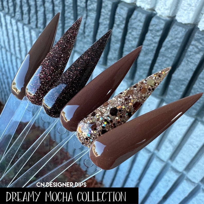 May include: Five different shades of brown nail dip powder, including a glitter option. The colors range from light to dark brown. The text "DREAMY MOCHA COLLECTION" is at the bottom of the image.  CN.DESIGNER.DIPS is at the top of the image.