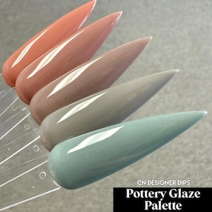May include: A palette of five nail polish samples in a variety of neutral colors. The colors include shades of peach, mauve, taupe, gray-green, and teal. The text "Pottery Glaze Palette" is displayed in a black rectangle.