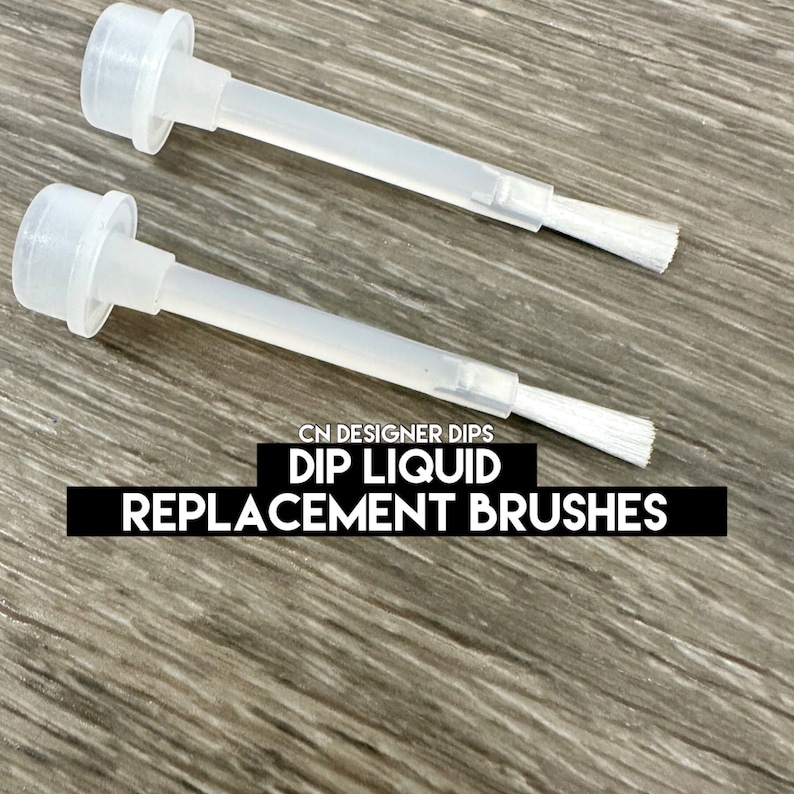 May include: Two clear plastic dip liquid replacement brushes with white bristles. The brushes have a cap and are labeled "CN DESIGNER DIPS DIP LIQUID REPLACEMENT BRUSHES."