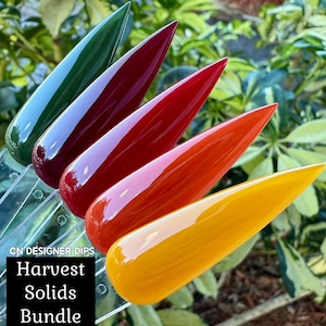 May include: A collection of four glossy nail polish samples in shades of green, burgundy, red-orange, and yellow. The text "CN DESIGNER DIPS" and "Harvest Solids Bundle" is displayed on a black background. The nail polish samples are arranged in a row.