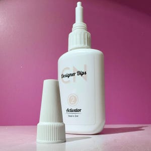 May include: White plastic bottle with a white cap and a label that says "CN Designer Dips" and "Activator" with a number "2" in a circle. The bottle is 56ml or 2oz.