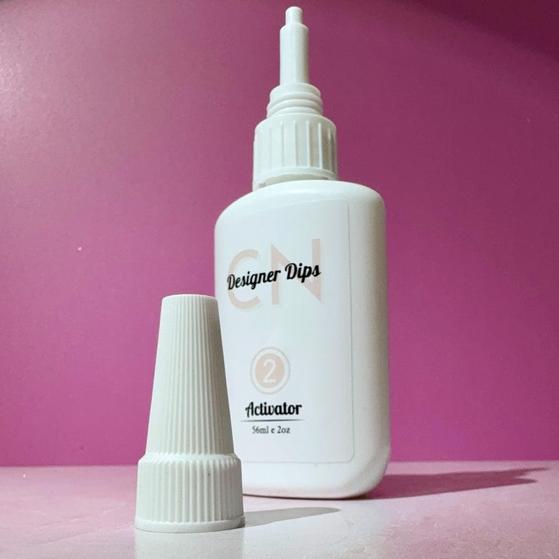 May include: White plastic bottle with a white cap and a label that says "CN Designer Dips" and "Activator" with a number "2" in a circle. The bottle is 56ml or 2oz.
