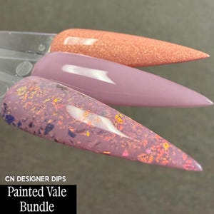 May include: Three stiletto-shaped nail swatches displayed on clear plastic sticks. The top swatch is a textured peach with fine shimmer, the middle is a smooth solid mauve, and the bottom is a mauve base with iridescent gold and blue flakes.