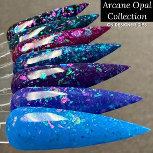 May include: Six nail dip samples in shades of blue, purple, and teal, with iridescent glitter. The text "Arcane Opal Collection" and "CN DESIGNER DIPS" are displayed. The samples are arranged in a row.