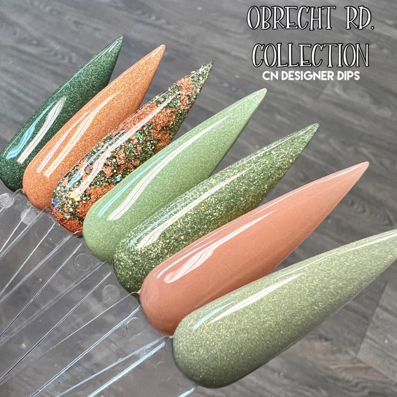 May include: A set of six nail dip powders in shades of green and brown with glitter. The set is called "Obrecht Rd. Collection" and is by CN Designer Dips.