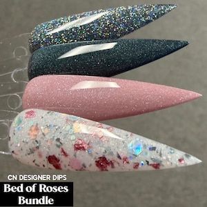 May include: Four stiletto-shaped nail polish swatches labeled CN DESIGNER DIPS Bed of Roses Bundle. The top swatch is silver glitter, the second is dark charcoal shimmer, the third is dusty rose shimmer, and the bottom is white with pink flakes.