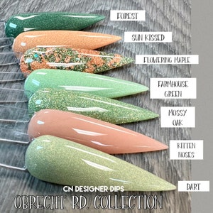 May include: A set of ten nail dip powder colors in a variety of green and peach shades. The colors are labeled "Forest", "Sun Kissed", "Flowering Maple", "Farmhouse Green", "Mossy Oak", "Kitten Noses", and "Dart". The set is labeled "CN Designer Dips Obrecht RD. Collection".