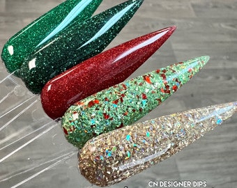 May include: Four nail polish colors in a Christmas theme. The colors are green, red, green with red glitter, and gold with iridescent glitter. The text on the image reads "CN Designer Dips Christmas Vol. 2".