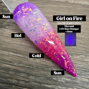 May include: A nail swatch with a color-changing effect. The nail is purple at the top, transitioning to pink at the bottom. The text "Girl on Fire" and "CN DESIGNER DIPS" are visible. The nail also changes color with UV light and glows.