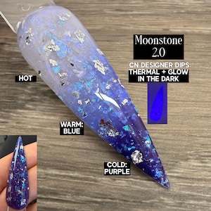 May include: A nail swatch with a color-changing design. The nail transitions from a light blue to a deep purple, with silver and blue glitter accents. The text on the image reads "Moonstone 2.0" and "Thermal + Glow in the Dark".