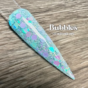 May include: A light blue nail dip powder with iridescent glitter and small, colorful hex glitter. The nail dip powder is called "Bubbles" and is from CN Designer Dips.