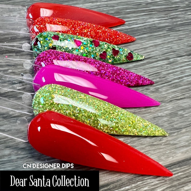 May include: A set of six nail dip powders in red, green, and pink shades with glitter. The set is labeled "Dear Santa Collection" and "CN Designer Dips".