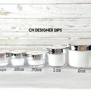 Op de afbeelding: Vijf doorzichtige plastic potten met zilveren deksels die witte poeder bevatten. De potten zijn gelabeld met de tekst "CN Designer Dips" en de maten "Sample", ".25oz", ".70oz", "1oz" en "2oz".