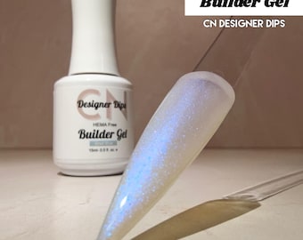 May include: A bottle of "Shell Blue Builder Gel" nail product with a white label and a clear applicator. The nail product is shown on a clear nail tip, displaying a shimmering blue and white color. The text "CN DESIGNER DIPS" is also visible.